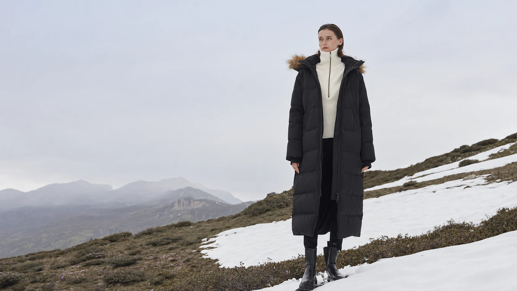 A woman wearing a black Waukee parka on a snowy mountainside.