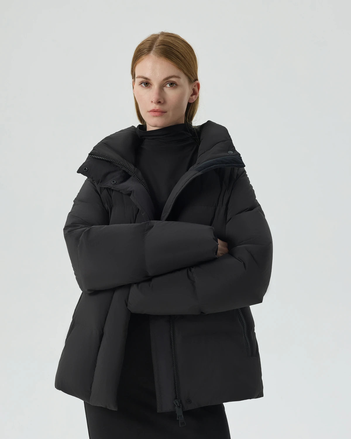A woman wearing a black Summit Breeze short down puffer with her arms crossed.